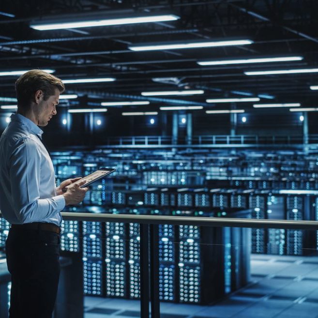man with tablet looking at servers