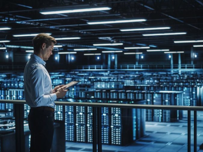 man with tablet looking at servers