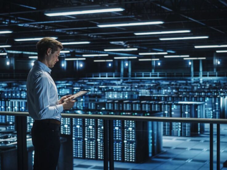 man with tablet looking at servers