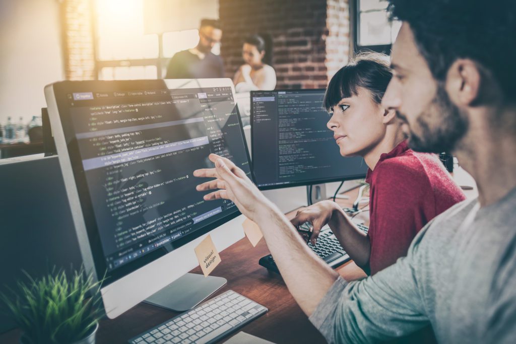 two people sitting next to each other at a computer monitor