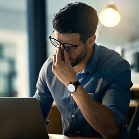 man frustrated sitting with a laptop