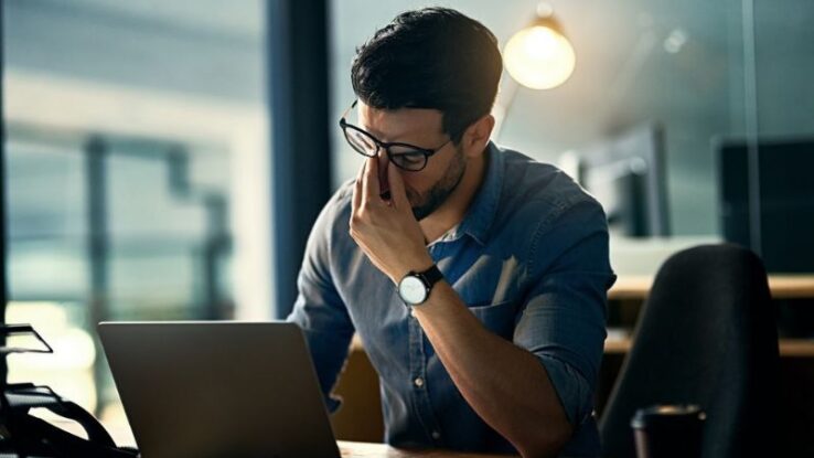 man frustrated sitting with a laptop