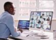man sitting at desk working remotely with zoom call active on screen