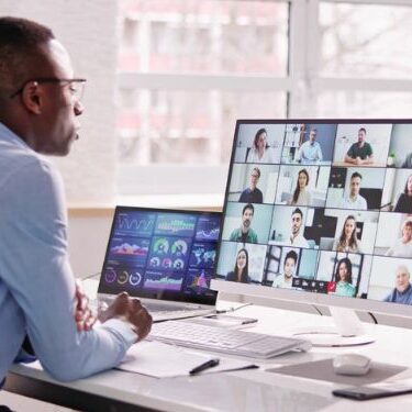 man sitting at desk working remotely with zoom call active on screen