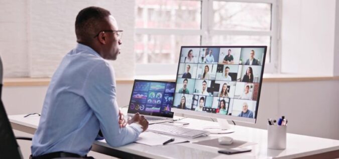 man sitting at desk working remotely with zoom call active on screen