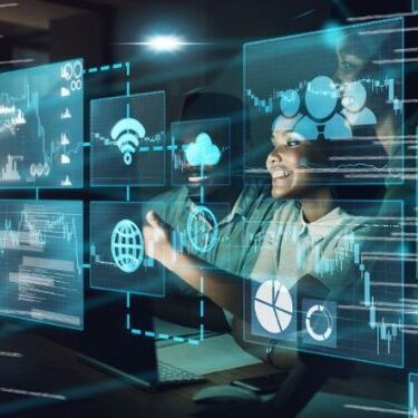 woman sitting infront of multiple transparent screens with computer code on them