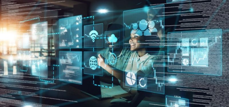 woman sitting infront of multiple transparent screens with computer code on them