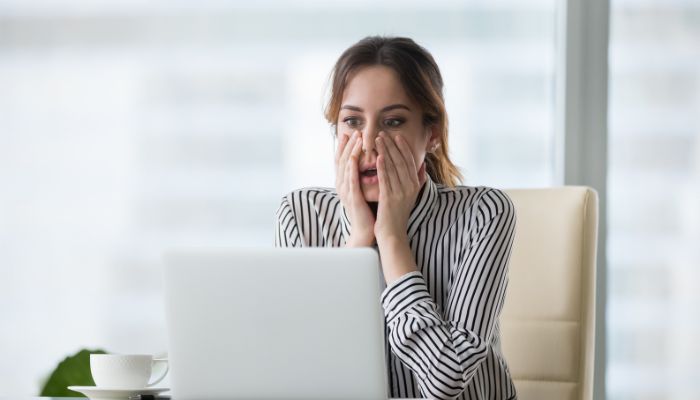 woman sitting at her desk stressed looking at her monitor