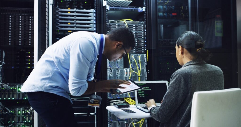 a man and woman working to fix a problem in a server room
